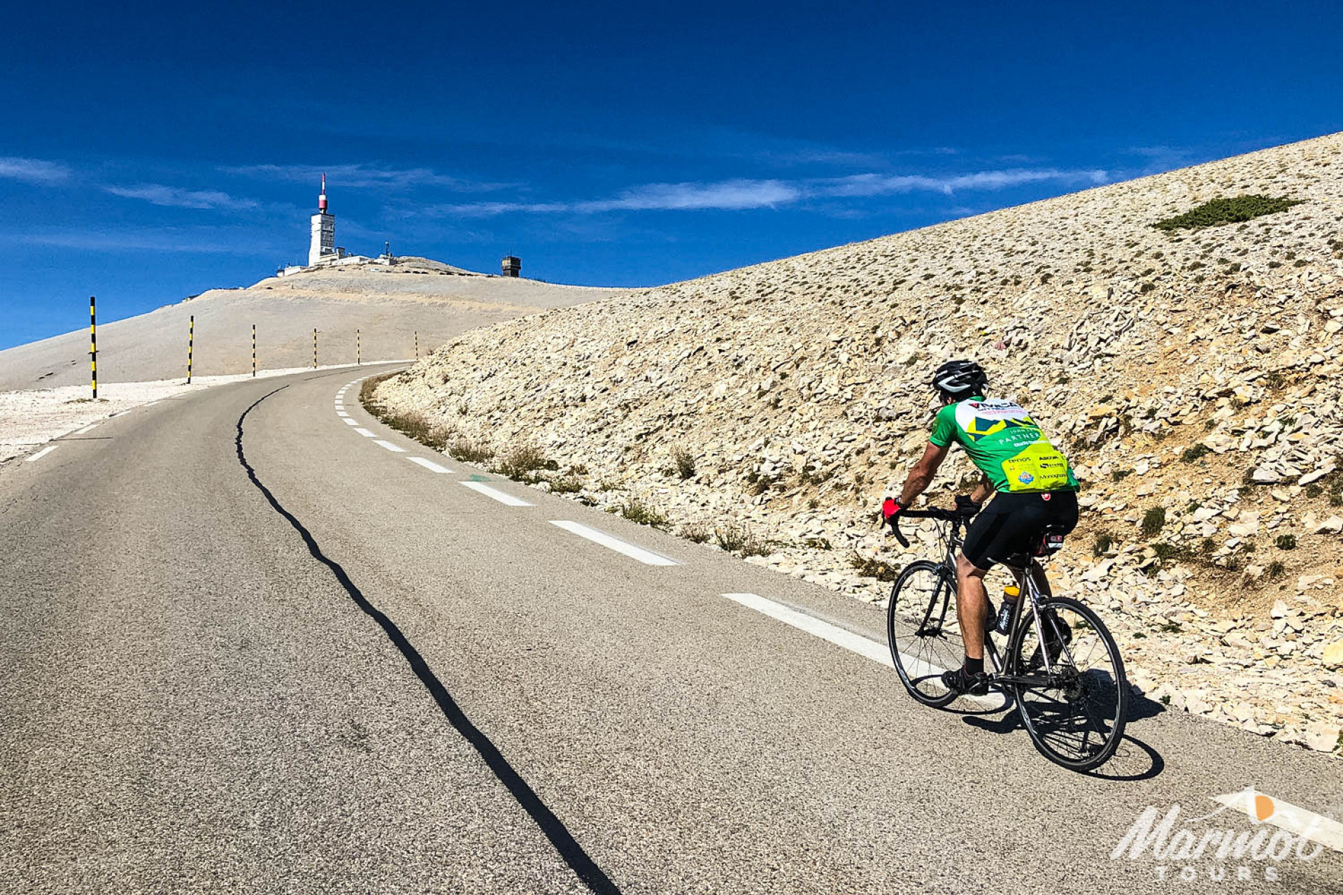 Cyclist on Mont Ventoux cycling climb on Marmot Tours hire bike beneath blue sky with summit in view