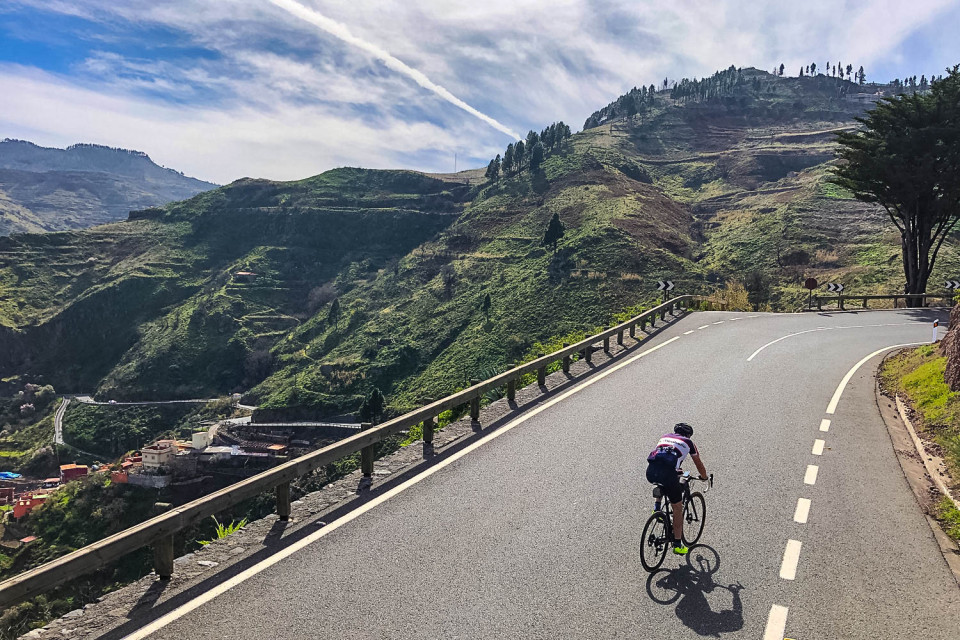 Cyclist climbing on road through lush vegetation slopes on full support guided road cycling tour Gran Canaria with Marmot Tours