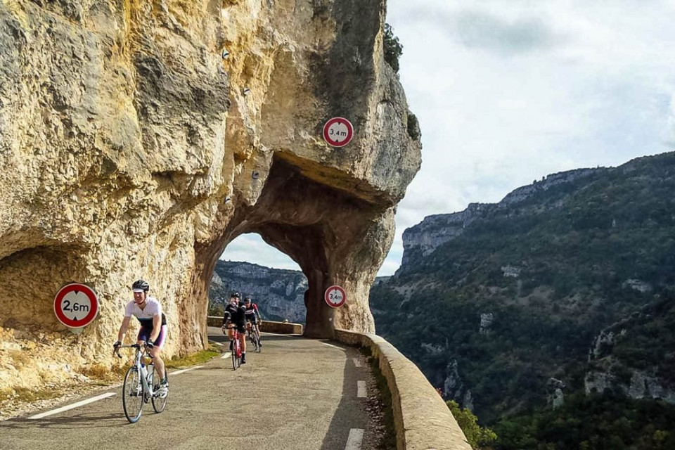 Group of cyclists on balcony road emerging from tunnel in Gorges de la Nesque cycling in Provence France with Marmot Tours
