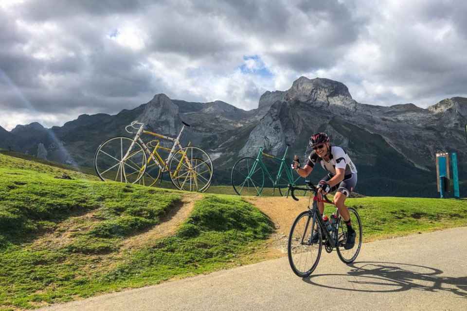 Cyclist giving thumbs up cycling past Col d'Aubisque on fully supported Raid Pyrenees challenge with Marmot Tours